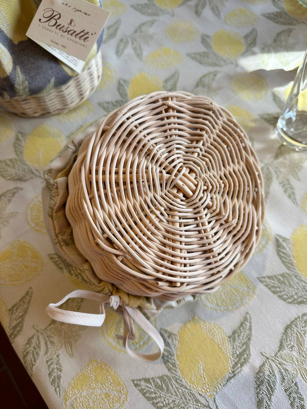 Woven basket with a white ribbon on a tablecloth with lemon pattern