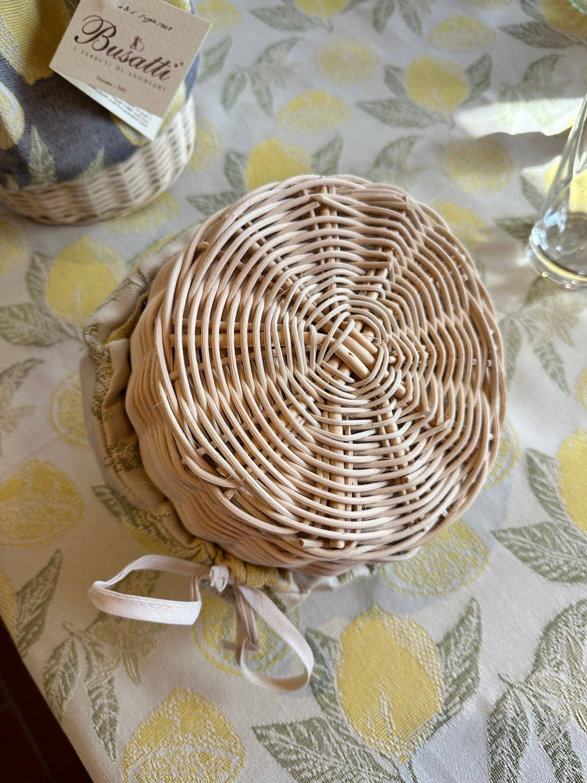 Woven basket with a white ribbon on a tablecloth with lemon pattern