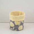 Fabric basket with yellow top and gray bottom featuring lemon pattern on a white background