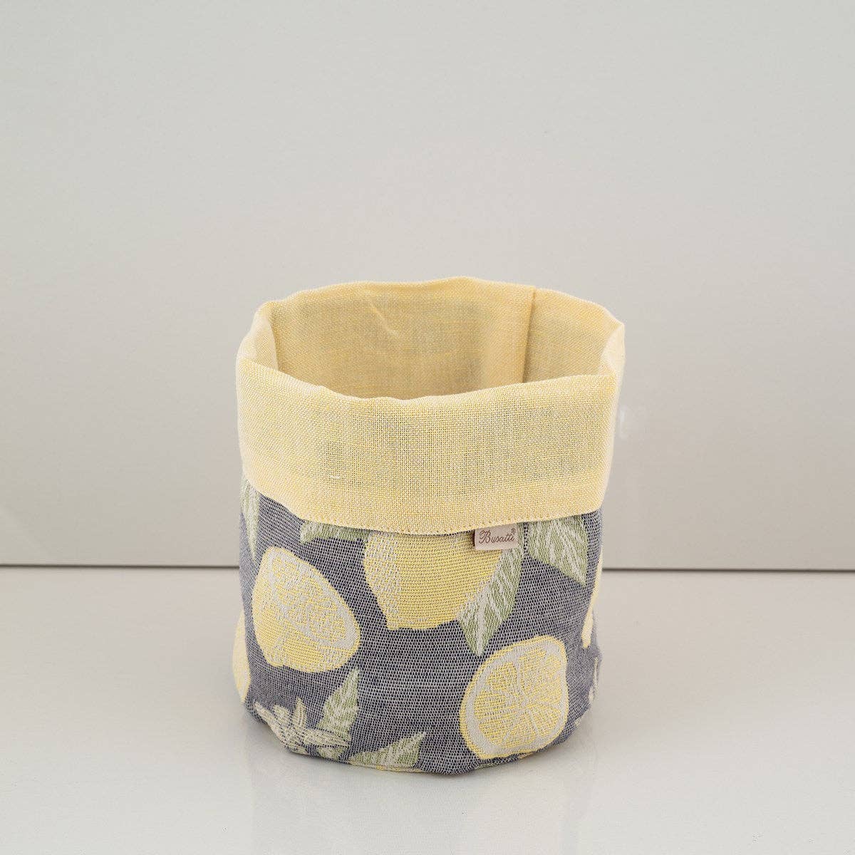 Fabric basket with yellow top and gray bottom featuring lemon pattern on a white background