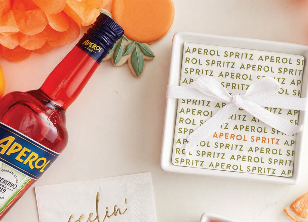 Aperol bottle with decorative coasters on a light surface