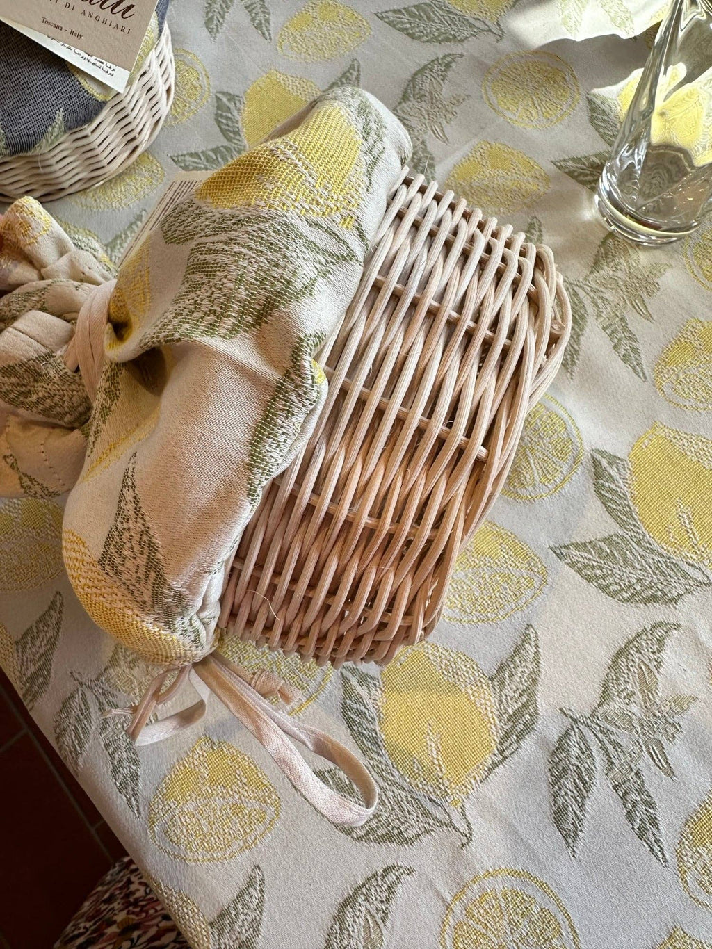 Wicker basket with a decorative cloth on a tablecloth with lemon pattern