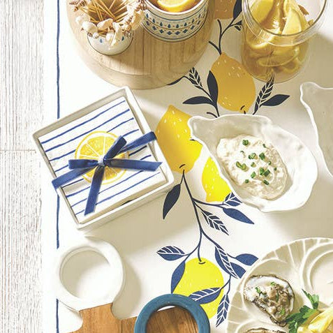 Table setting with decorative plates, cutting boards, and glasses on a light wooden surface.